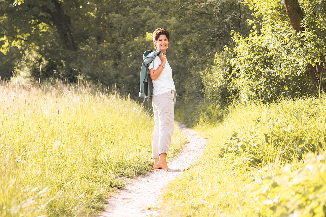 Nicole Oertli geht auf einem Weg in der Natur, lächelt zurück, Einladung zu persönlichen Beratungsgesprächen.