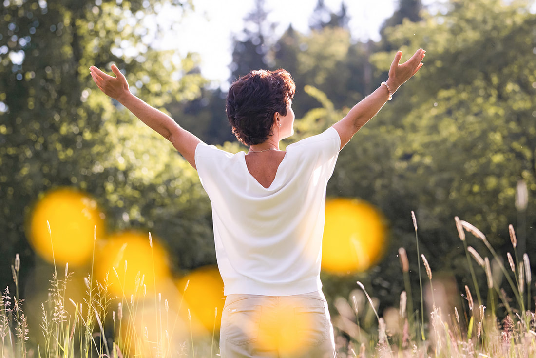 Nicole Oertli öffnet Arme in Abendsonne, empfängt neue Energie, symbolisiert Transformation beim ThetaHealing.